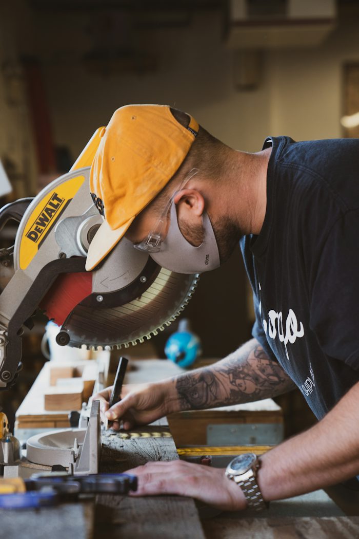 Carpenter cutting timber with a mitre saw at the workshop bench